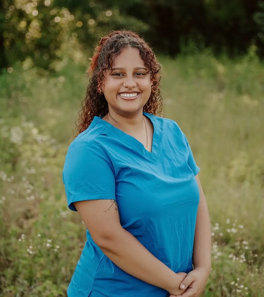 Female with long curly hair wearing blue scrubs