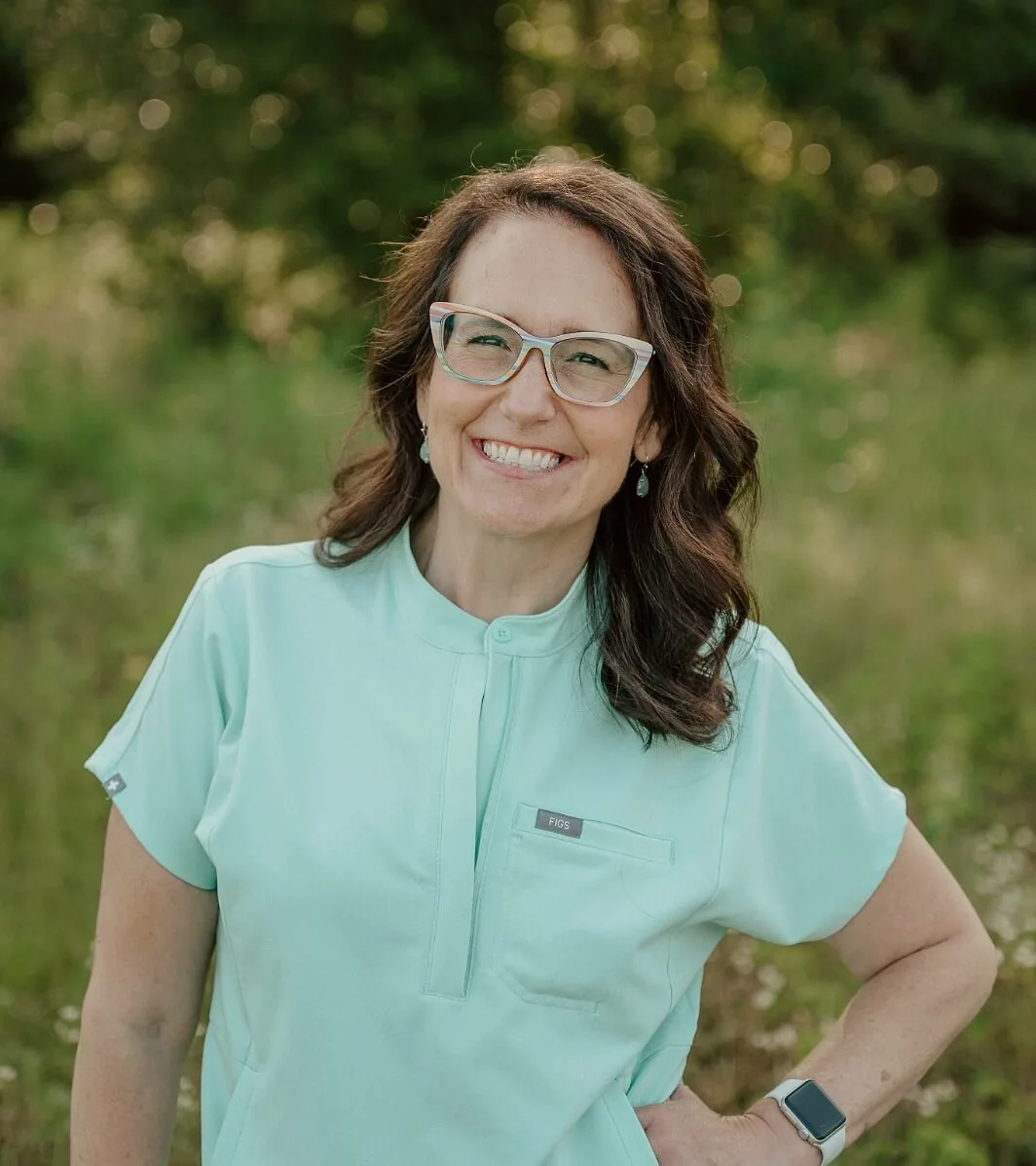Female with medium length brown hair and glasses wearing mint green scrubs