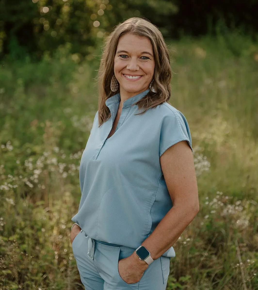 Female with shoulder length brown hair posing with hands in pocket