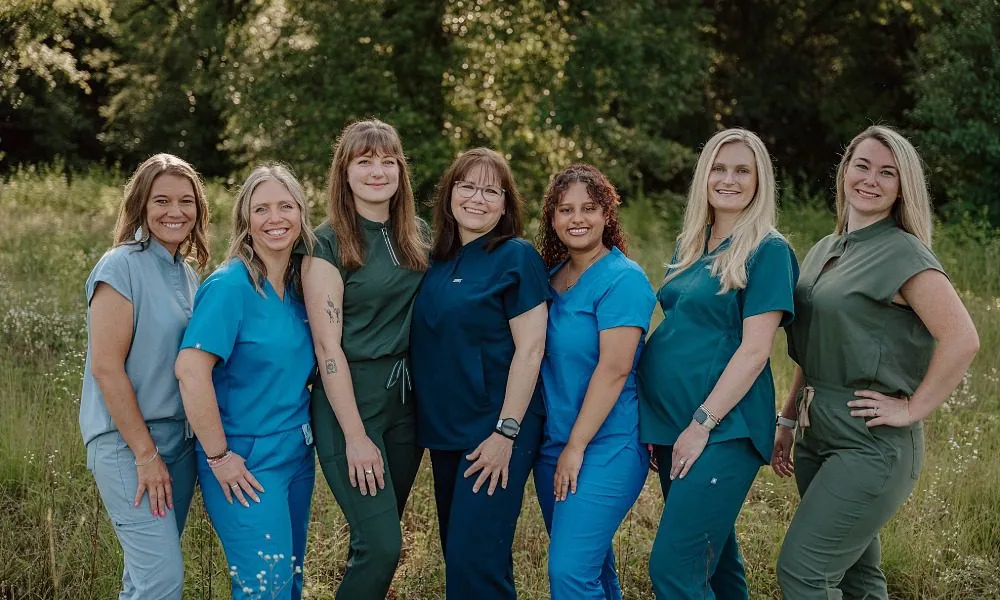 Group photo of Vet techs and assistants wearing different shades of blue scrubs